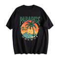 A black short-sleeve t-shirt with a retro-style tropical graphic on the front. The graphic features the word 'PARADISE' in green, a palm tree silhouetted against an orange sunset, the text 'LIVE THE TROPICAL', and coordinates '25° 46' N / 80° 12' W'.
