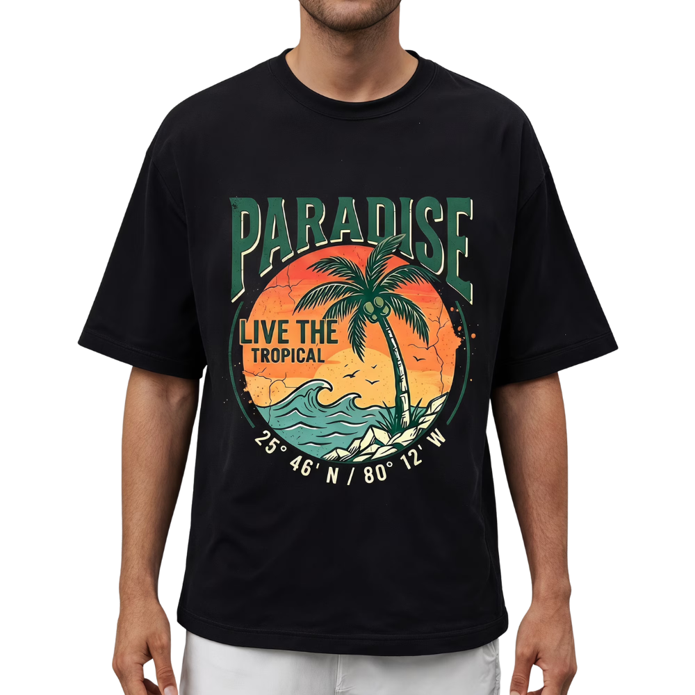 A man wearing a black short-sleeve t-shirt with a colorful tropical graphic on the front featuring a palm tree, waves, and the text 'PARADISE LIVE THE TROPICAL'.