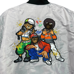Close-up of the back of a shiny light gray bomber jacket with a large colorful cartoon graphic of three teddy bears in streetwear, including one wearing a green bag and the other in a red jacket. The collar is black.