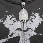 Close-up of a black zip-up hoodie with a distressed gray graphic print and a highly detailed silver metal zipper pull featuring a winged skull design.