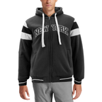 A man wearing a black zip-up hoodie with white drawstrings, white shoulder stripes, and 'NEW YORK' printed across the chest in white outlined lettering, paired with gray pants against a white background.